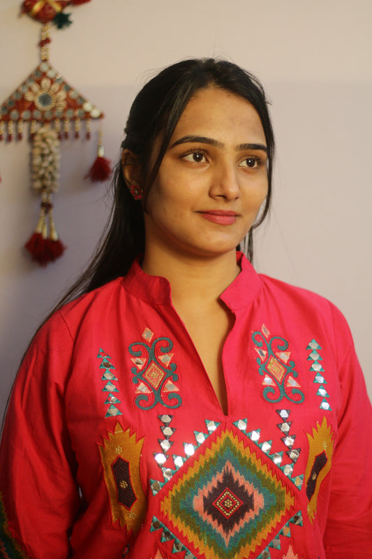 Woman wearing a red embroidered traditional outfit with a plain background