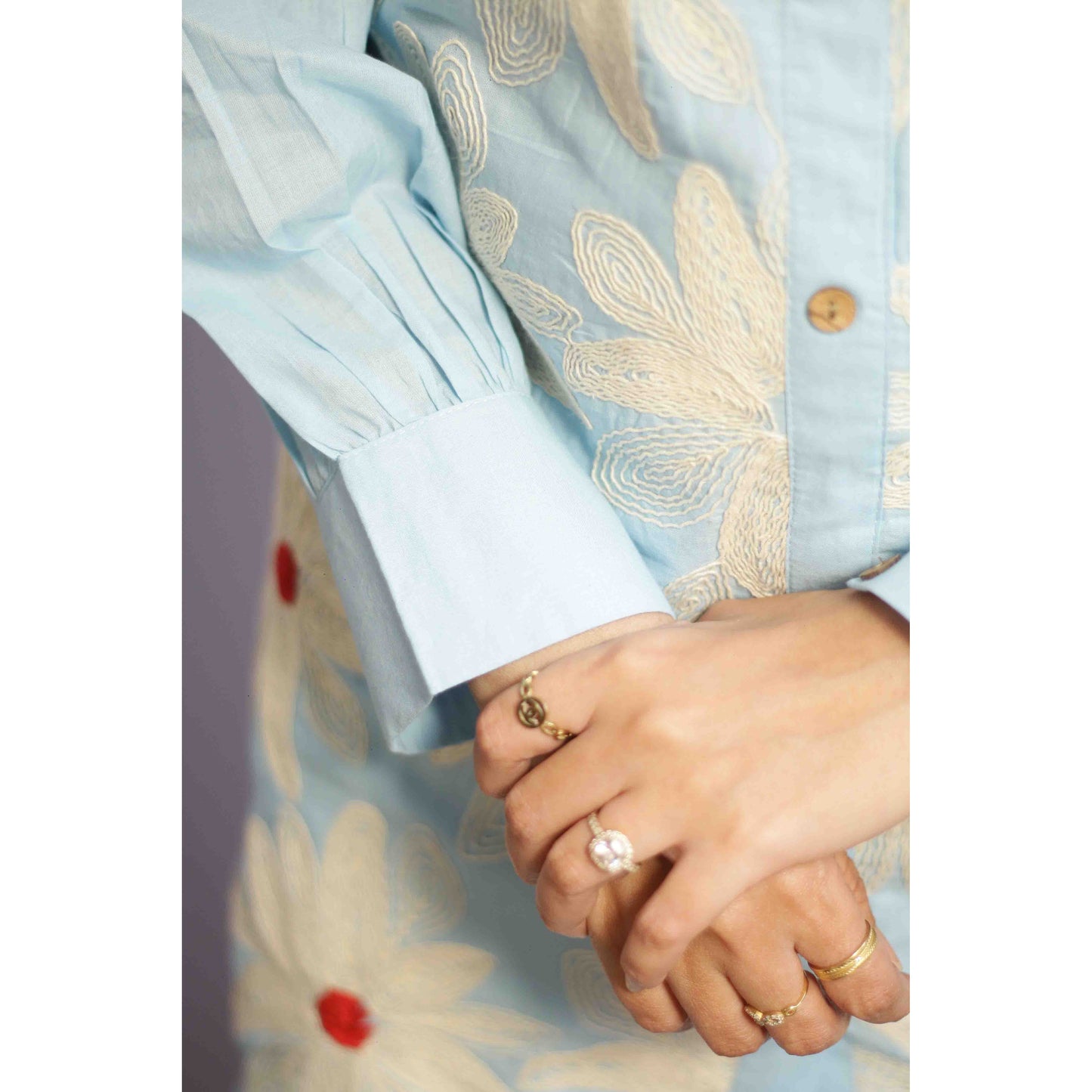 Woman wearing a light blue traditional outfit with red polka dots with Cord work Embroidery