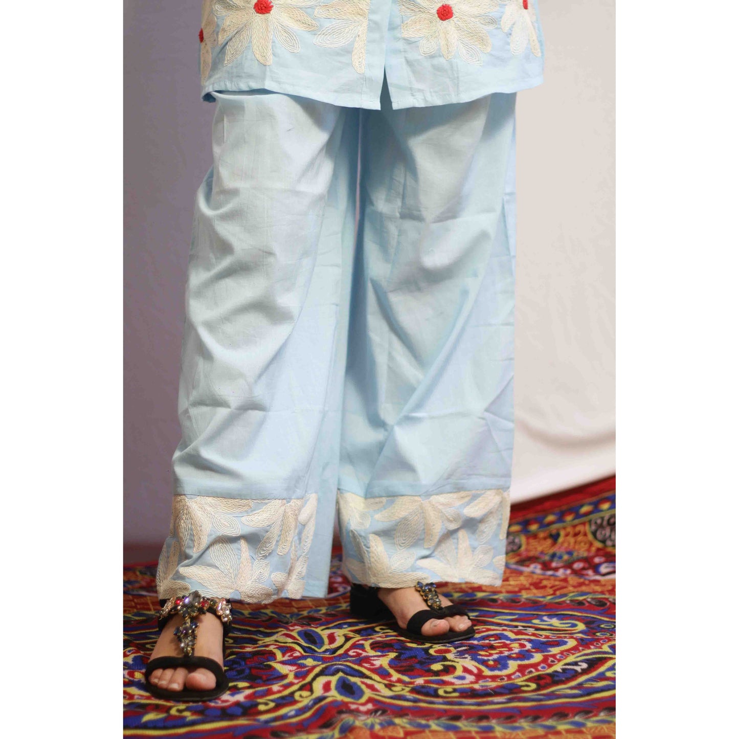 Woman wearing a light blue traditional outfit with red polka dots with Cord work Embroidery