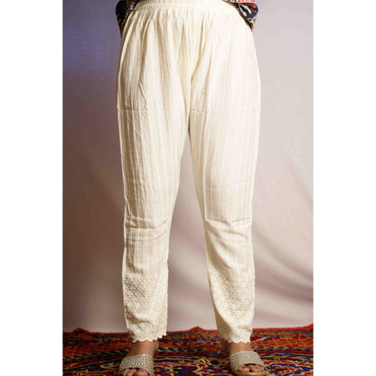 White pants worn by a person on a colorful rug with a plain background