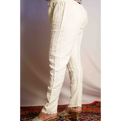 White pants with lace trim worn by a person on a patterned rug.