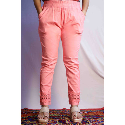 Person wearing pink pants with lace details on a patterned rug