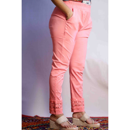 Person wearing pink pants with lace details on a plain background