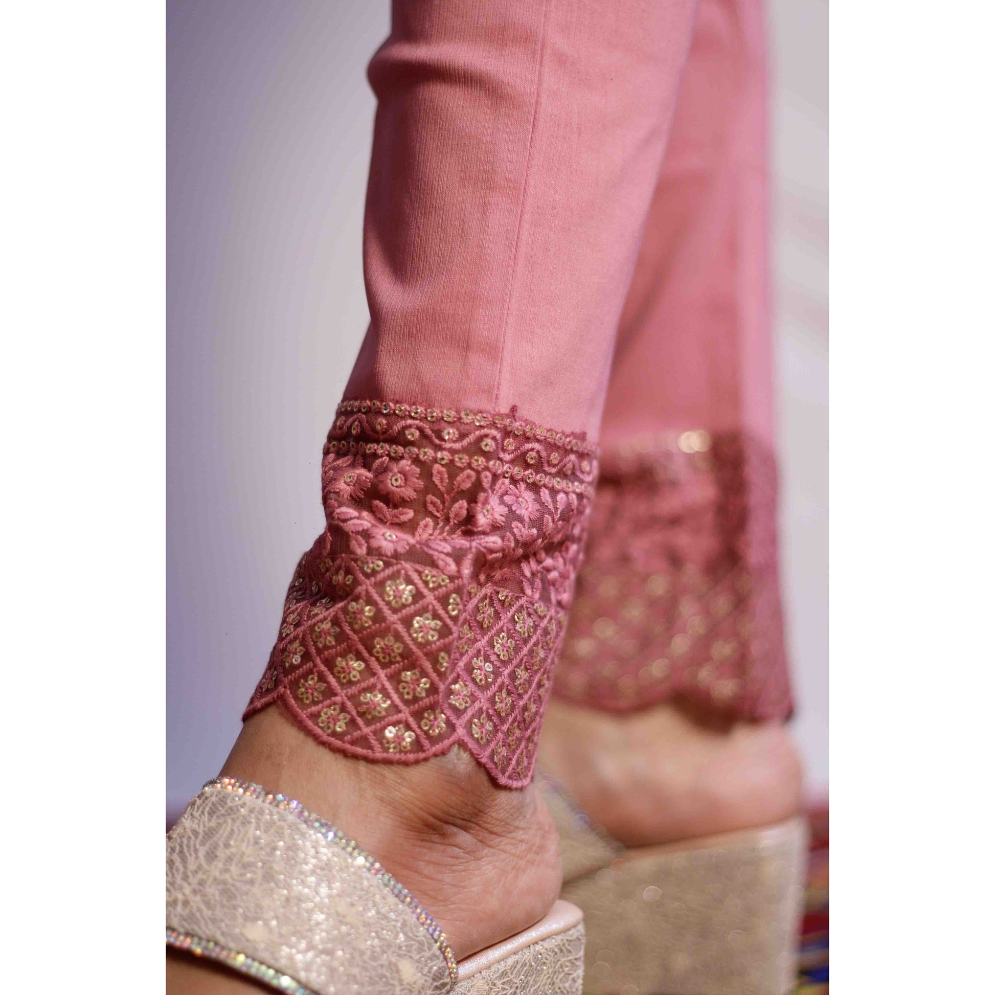 Close-up of pink embroidered anklets on a foot with a blurred background