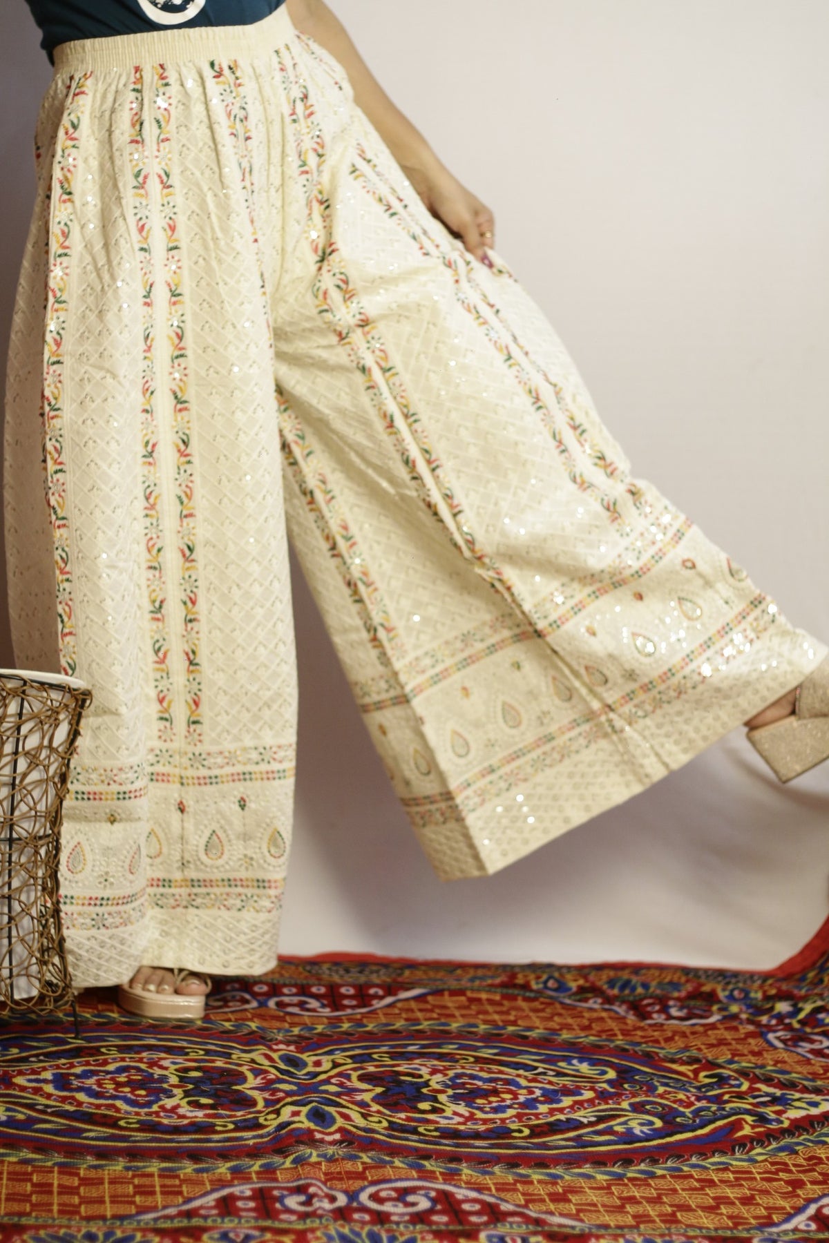 Beige wide leg palazzo held open to show the full flare and paisley hem border