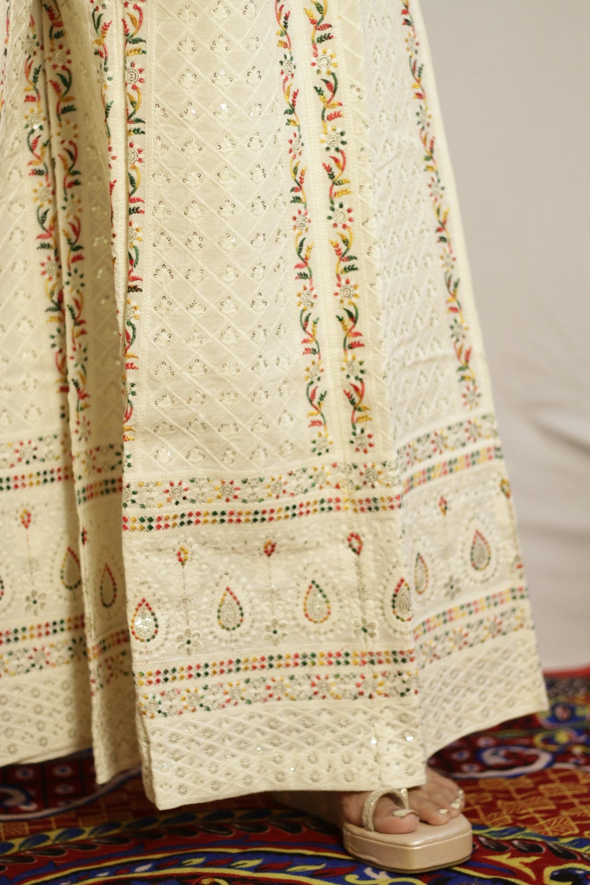 Close up of the paisley embroidered border at the hem of the beige palazzo