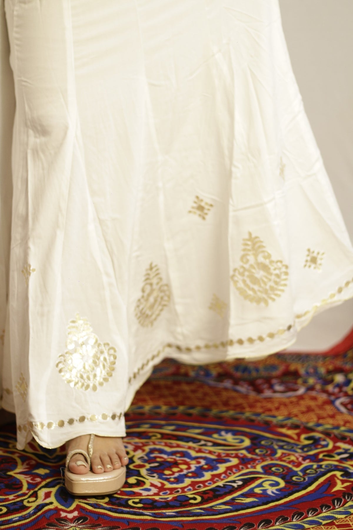 Close up of gold gotta patti work and disc trim on the white palazzo hem