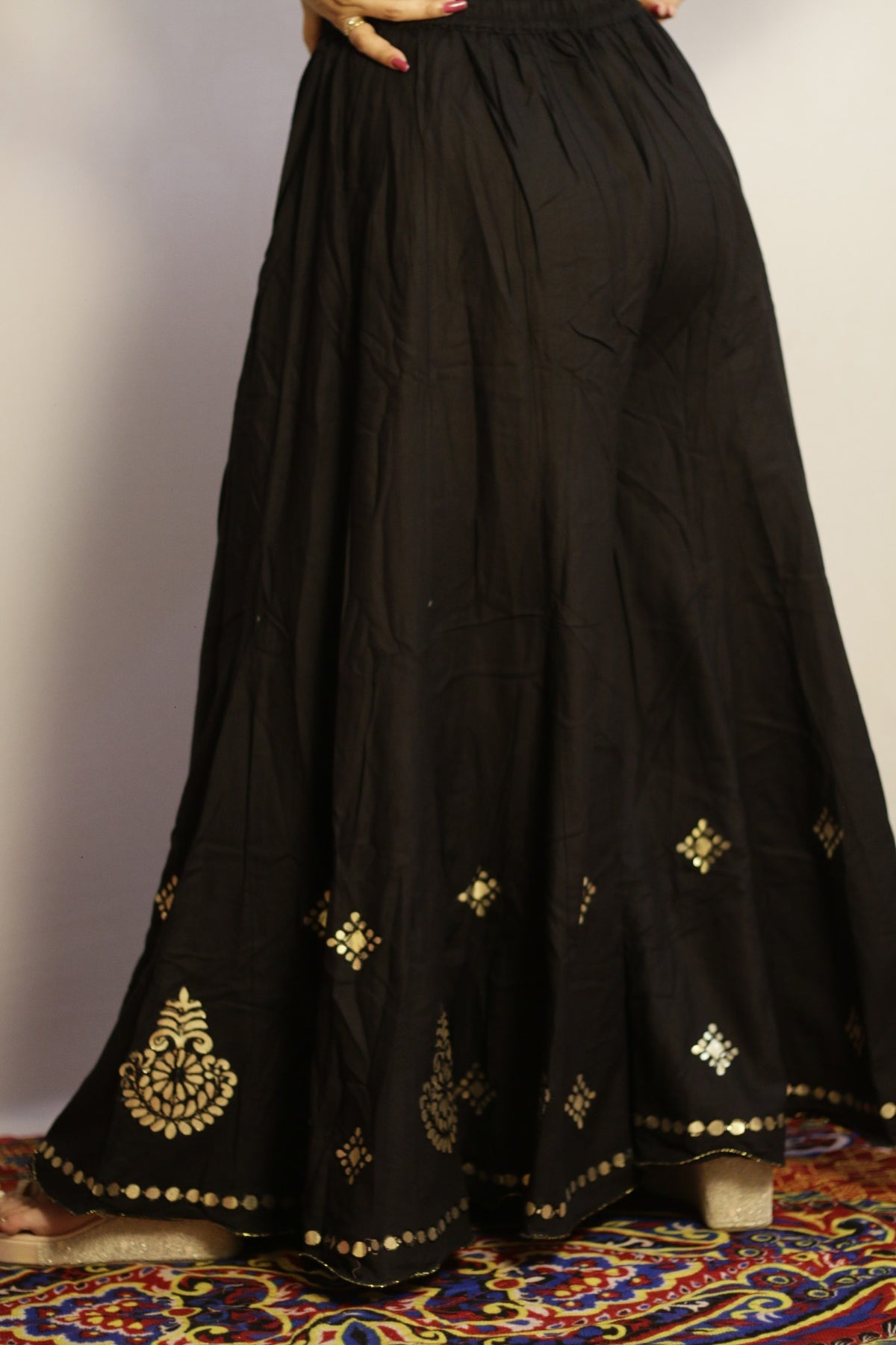 Back view of the black gotta patti palazzo with gold disc trim along the hem