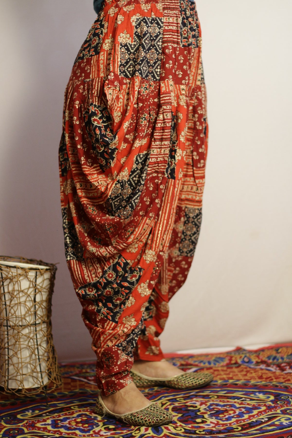 Red dhoti pant side view showing the deep drape and navy print blocks
