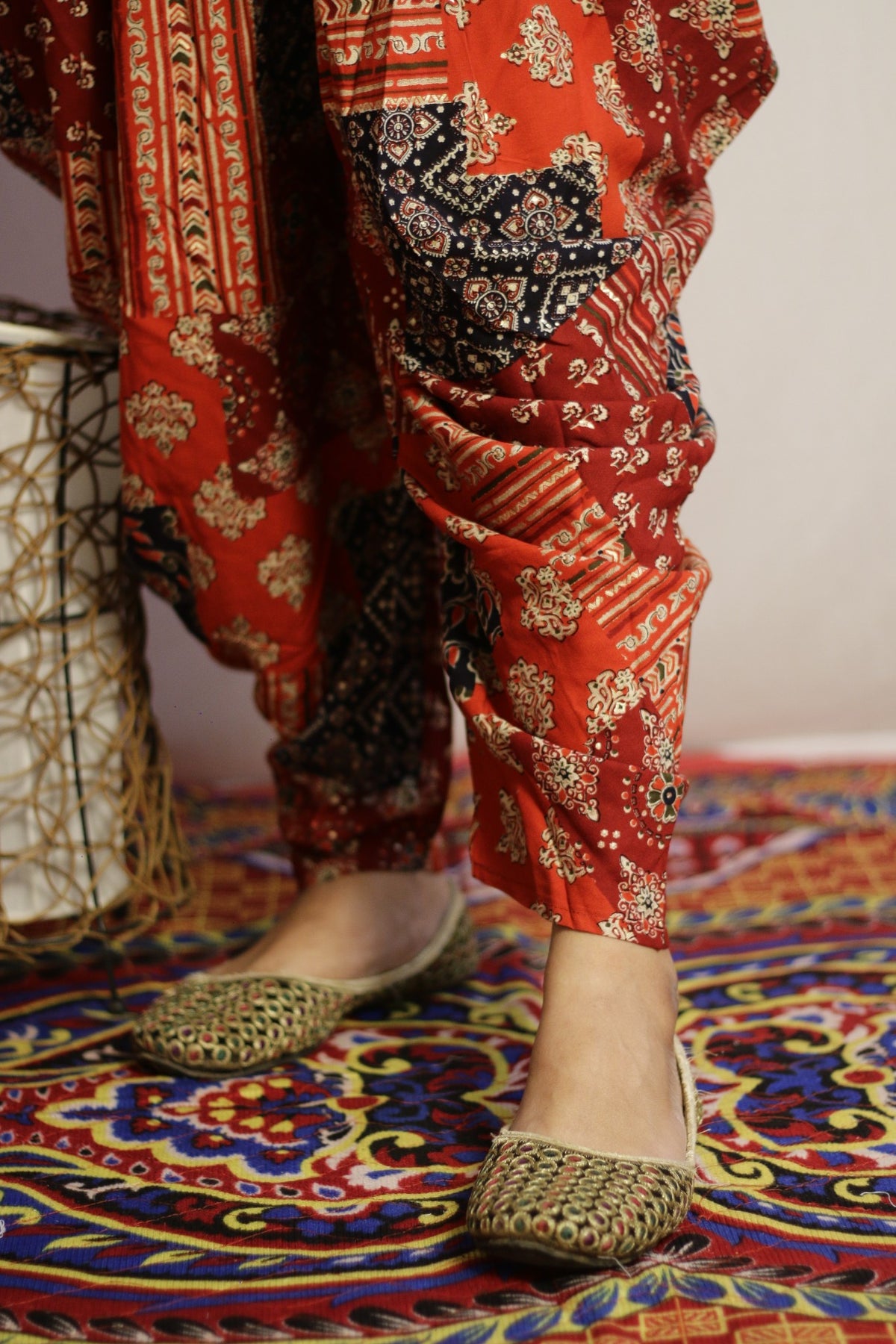 Close up of the tapered ankle and cream and gold print on the red dhoti pant