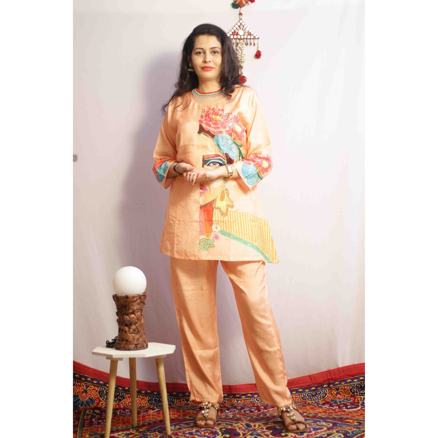 Woman wearing a traditional outfit with colorful embroidery in a decorated room.
