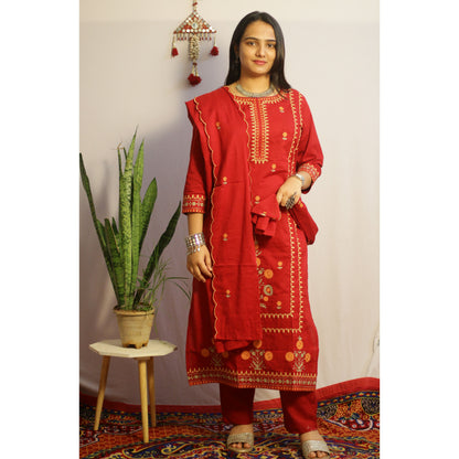 Woman wearing a red traditional outfit with gold embroidery in a decorated room.