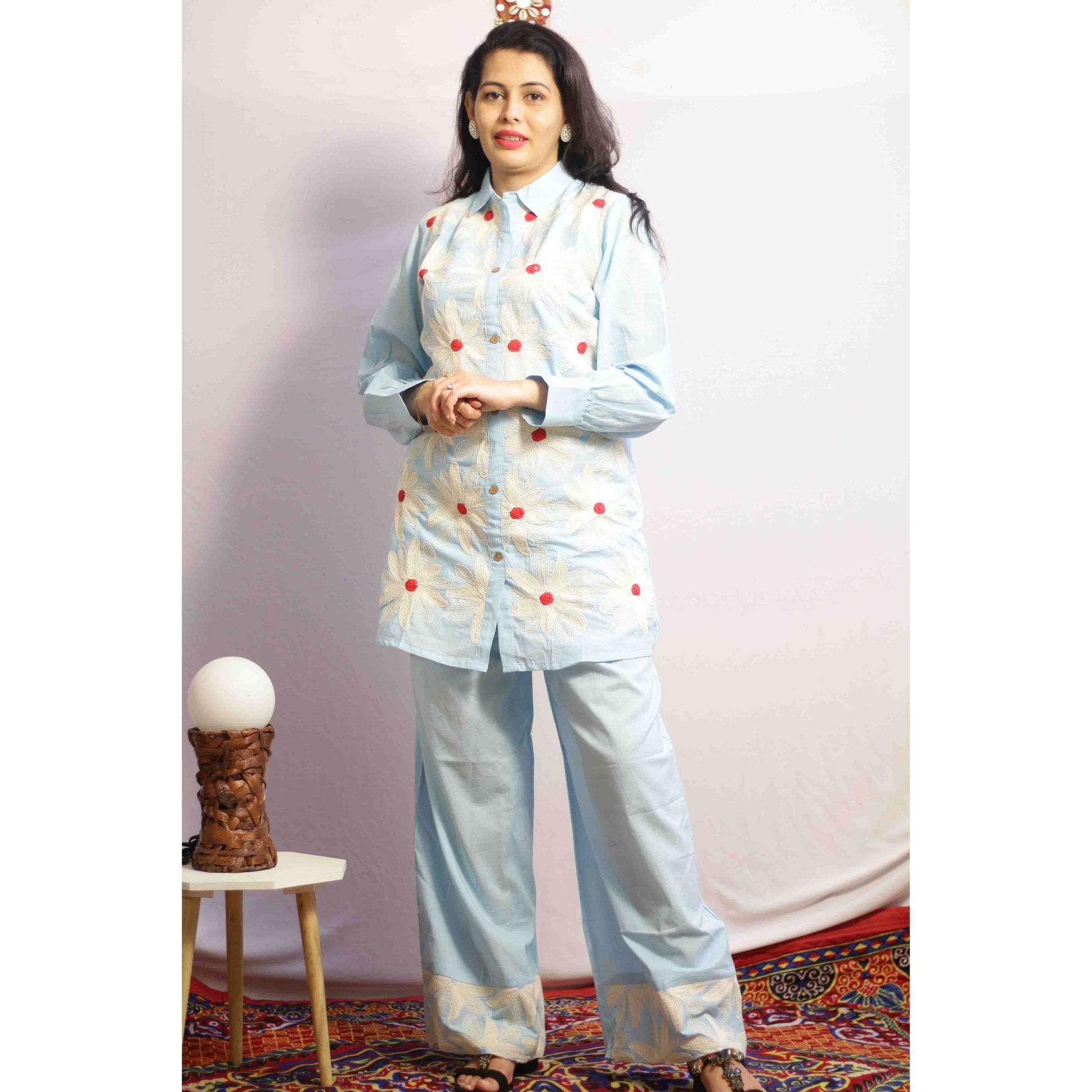 Woman wearing a light blue traditional outfit with red polka dots with Cord work Embroidery