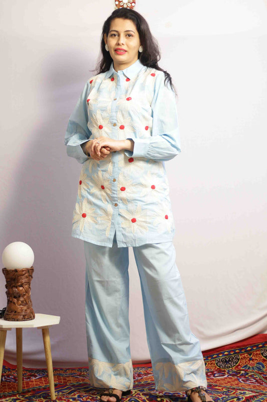 Woman wearing a light blue traditional outfit with red polka dots with Cord work Embroidery